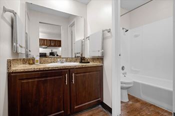 A bathroom with a white tub and wooden cabinets. at Malvern Hill Apartment Homes, 66103, KS, 66214